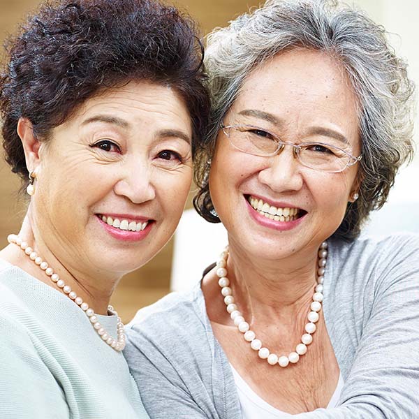 gleichgeschlechtliches weibliches Paar mit asiatischen Aussehen, das zusammen lächelnd in die Kamera schaut